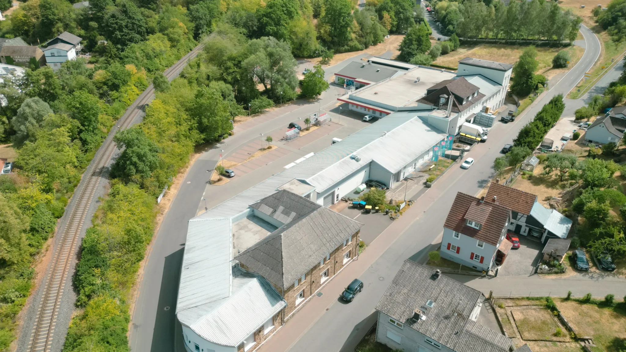 Luftbild des Aubach-Geländes in Waldsolms mit Bahnlinie, Parkplatz und viel Grün