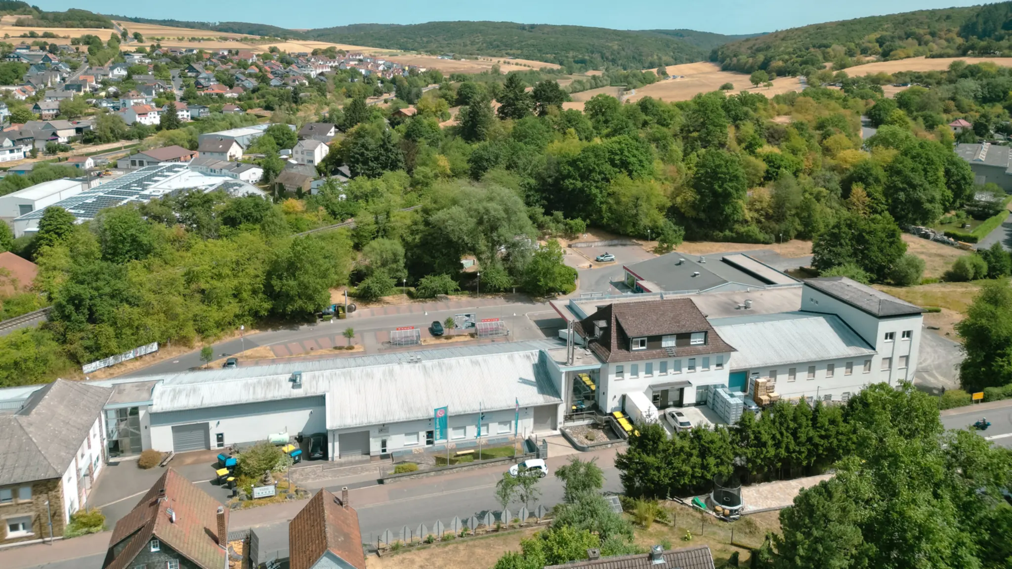 Luftbild Treffpunkt Aubach in Waldsolms: Nahversorgungszentrum mit Parkplatz, umgeben von Grün